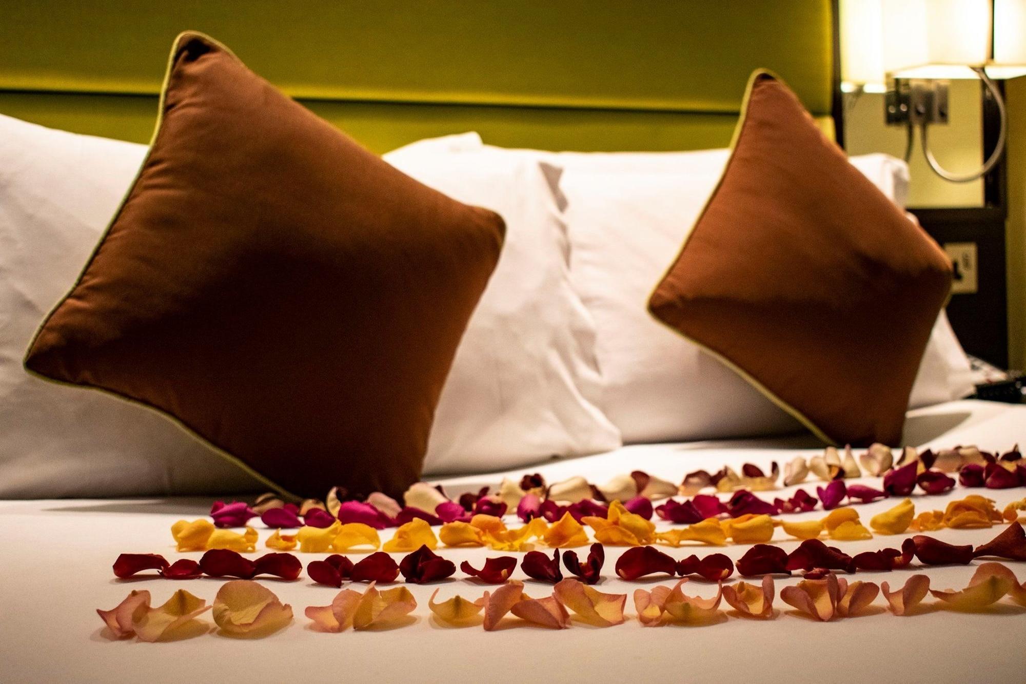 Отель Montcalm Brewery Townhouse Лондон Экстерьер фото The photo shows a neatly arranged bed with two white pillows and brown decorative cushions. Scattered across the bed is a decorative display of flower petals in various colors, including pink, yellow, and orange, creating a romantic or tranquil ambia
