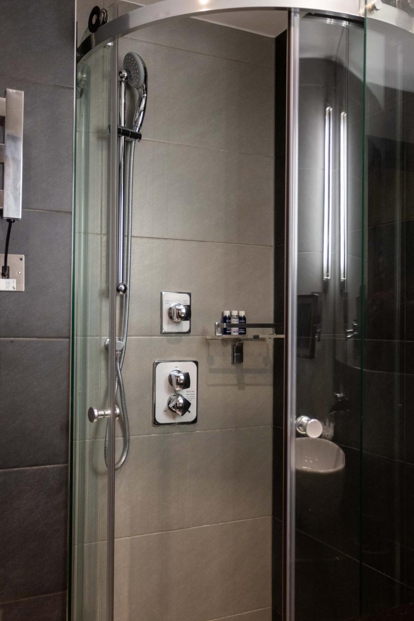 Отель Montcalm Brewery Townhouse Лондон Экстерьер фото The photo shows a modern shower area. It features glass panels and tiled walls in a neutral color palette, creating a sleek and contemporary look. There are two main control panels for adjusting the water temperature and pressure, with various knobs 