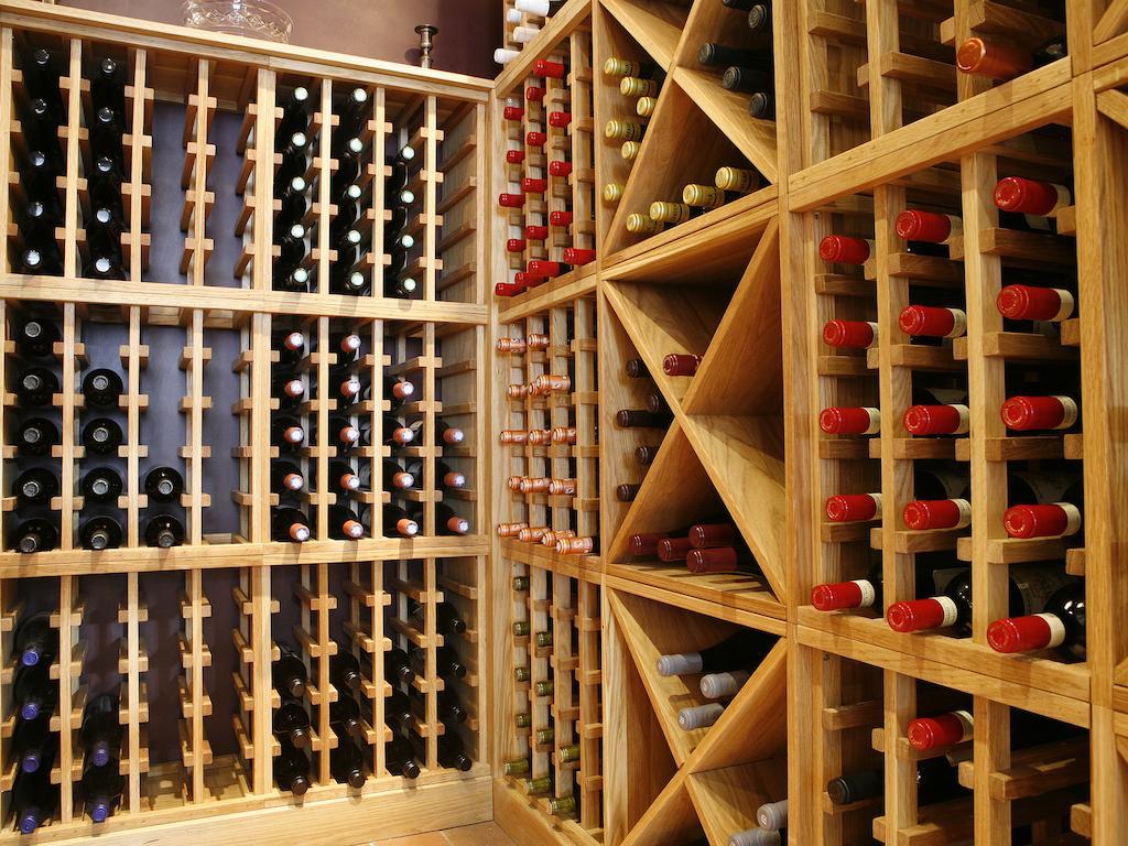 Отель Montcalm Brewery Townhouse Лондон Экстерьер фото The photo shows a wine cellar with wooden racks designed for storing wine bottles. The structure is divided into sections, featuring various compartments that hold the bottles in an organized manner. The bottles have different colors, with many red a